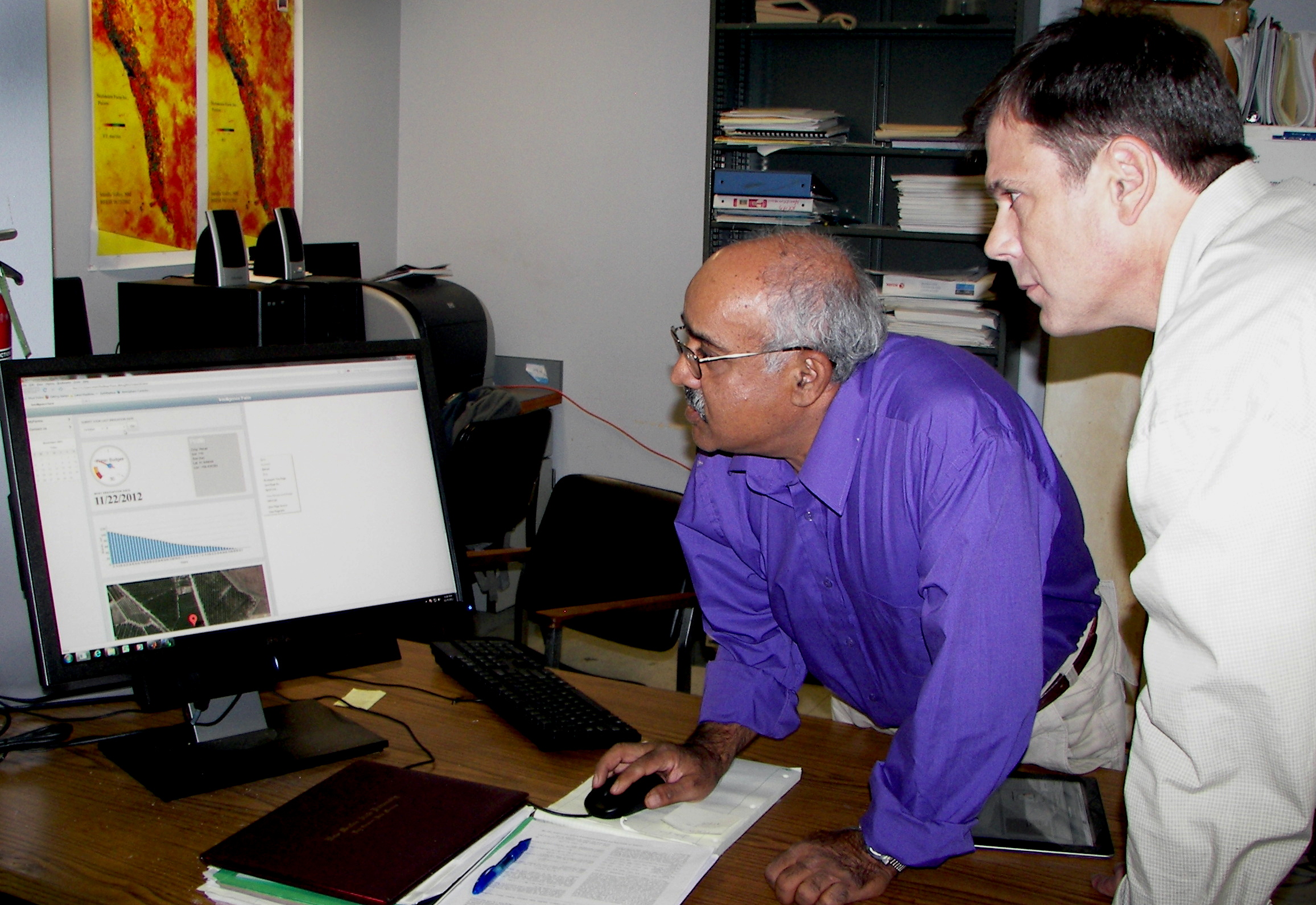 two men look at a computer 