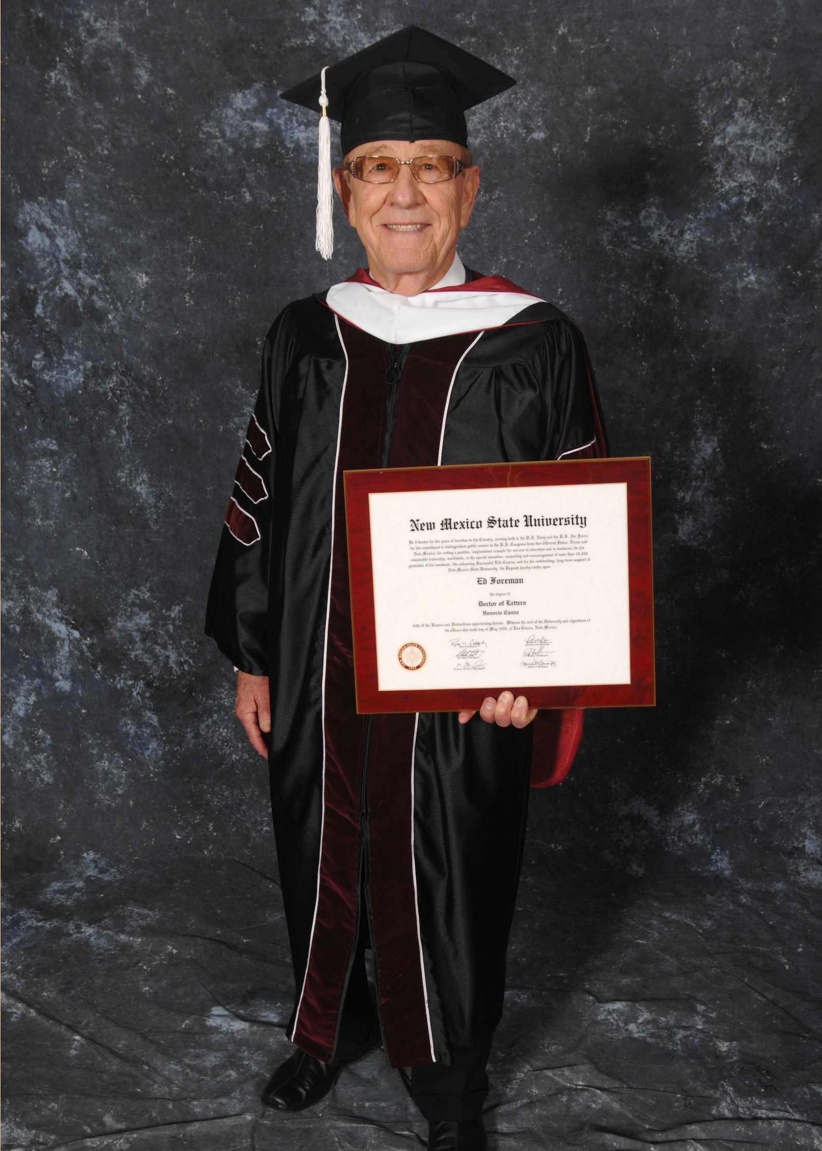 Man holds a degree wearing commencement regalia 