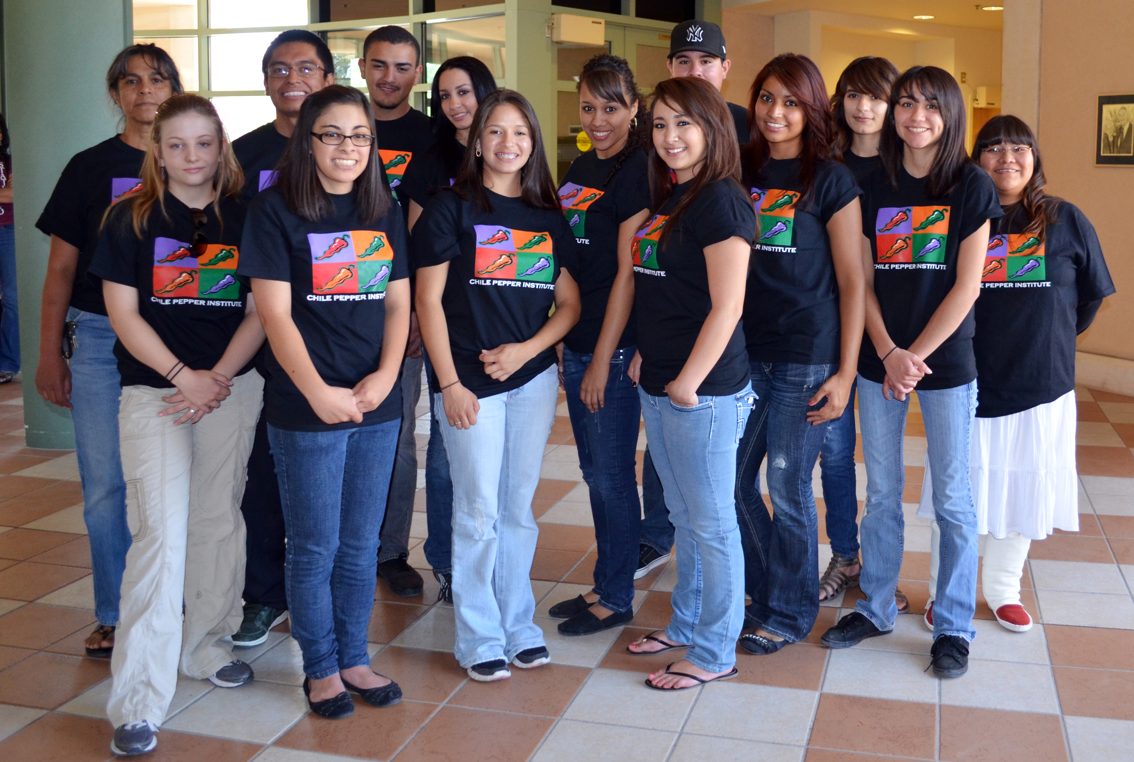 Group of 12 students pose for camera with one faculty member and one graduate student, all wearing black T-shirts.