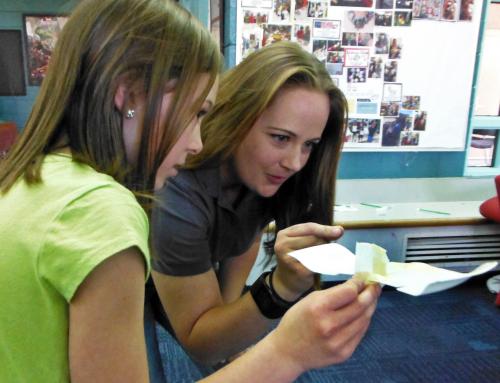 Woman looking at a paper airplane held by a girl.