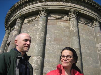 Man and woman from the waist up with old building in the background