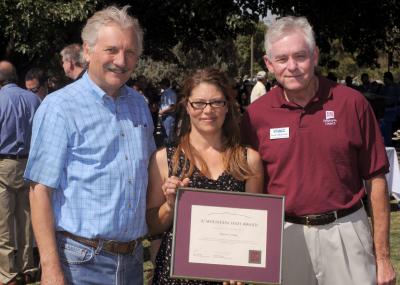 three people one holding plaque