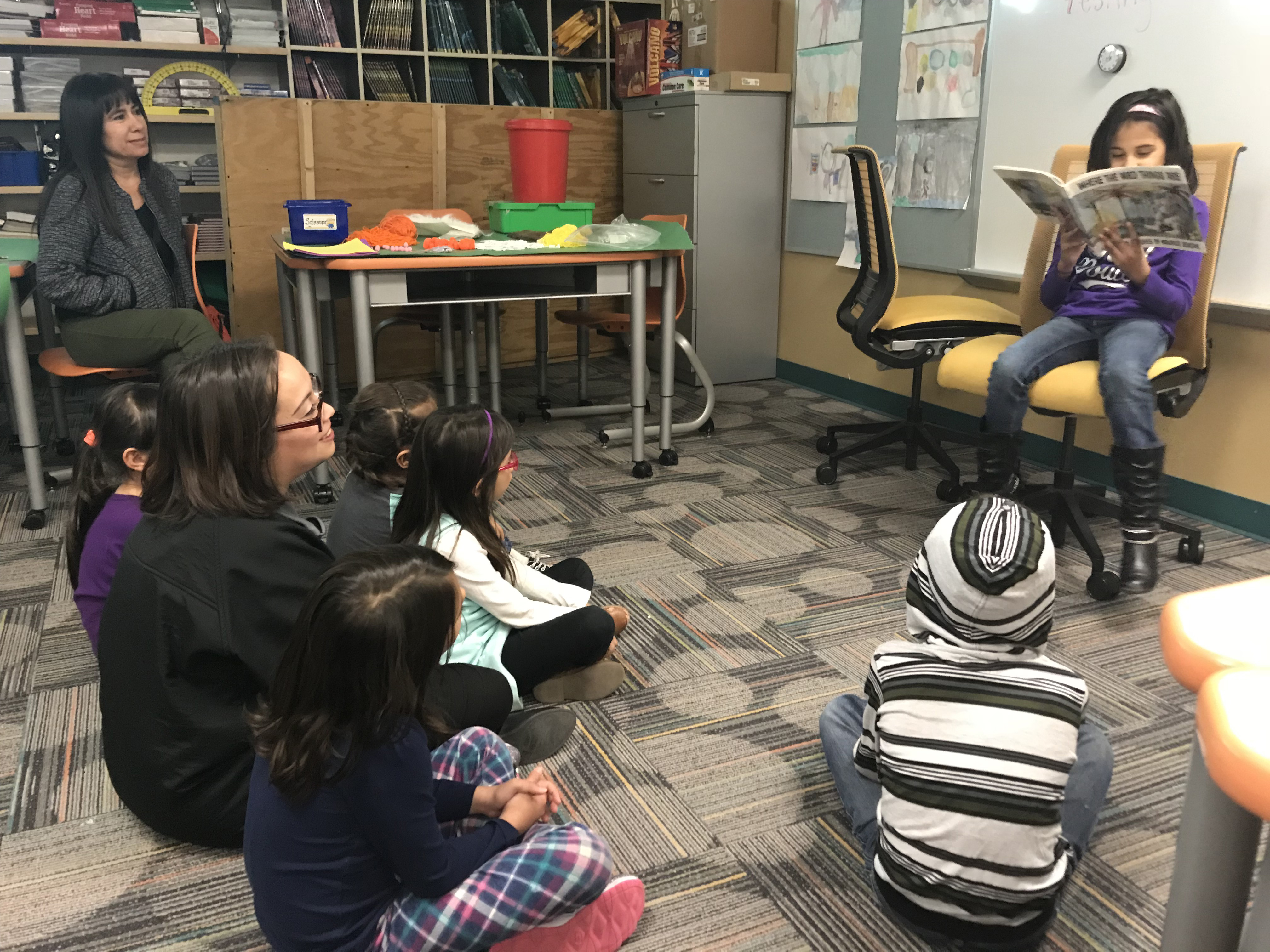 Child reading a book in front of a class