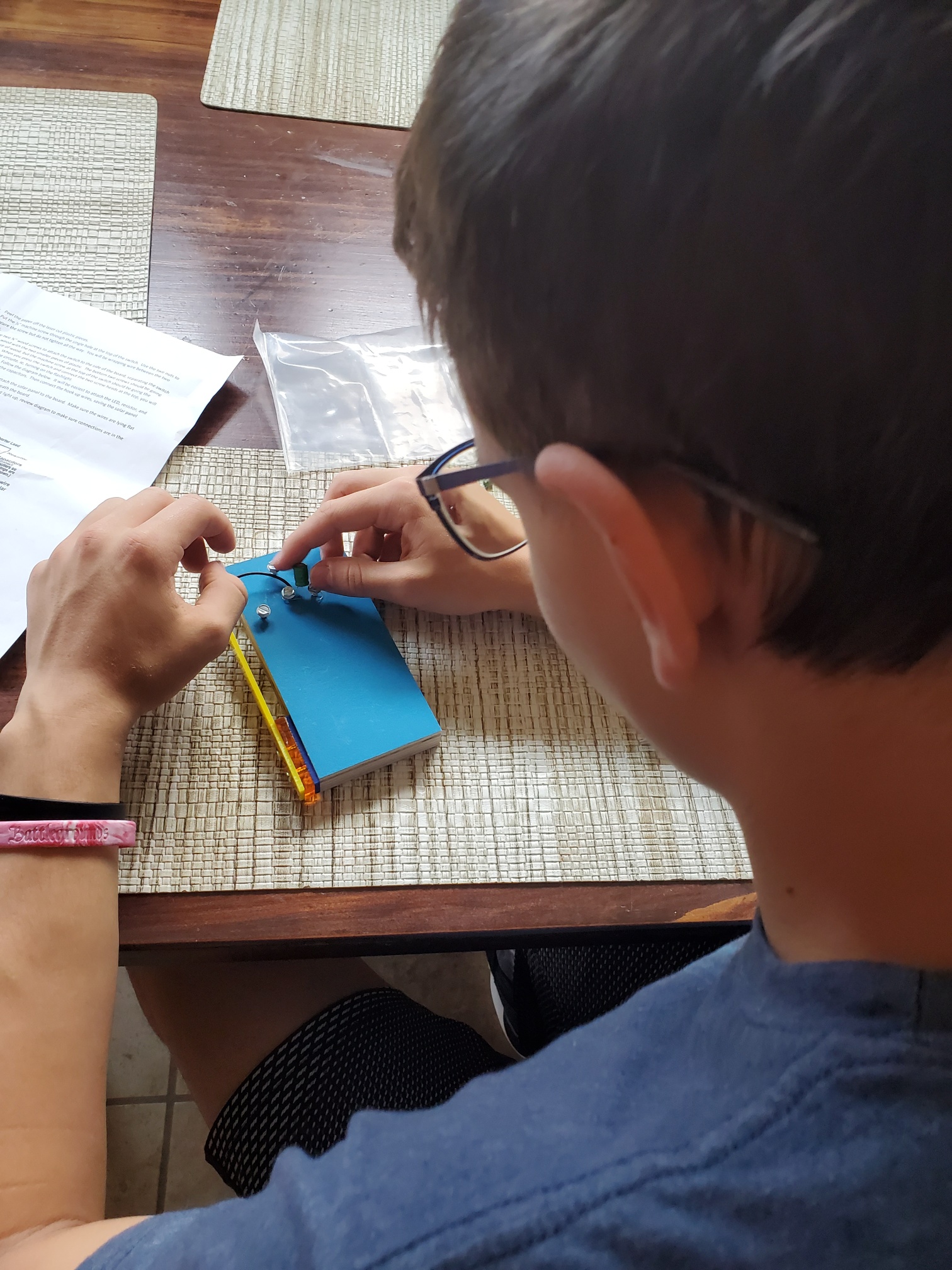 Young boy, wearing glasses, builds a flashlight.