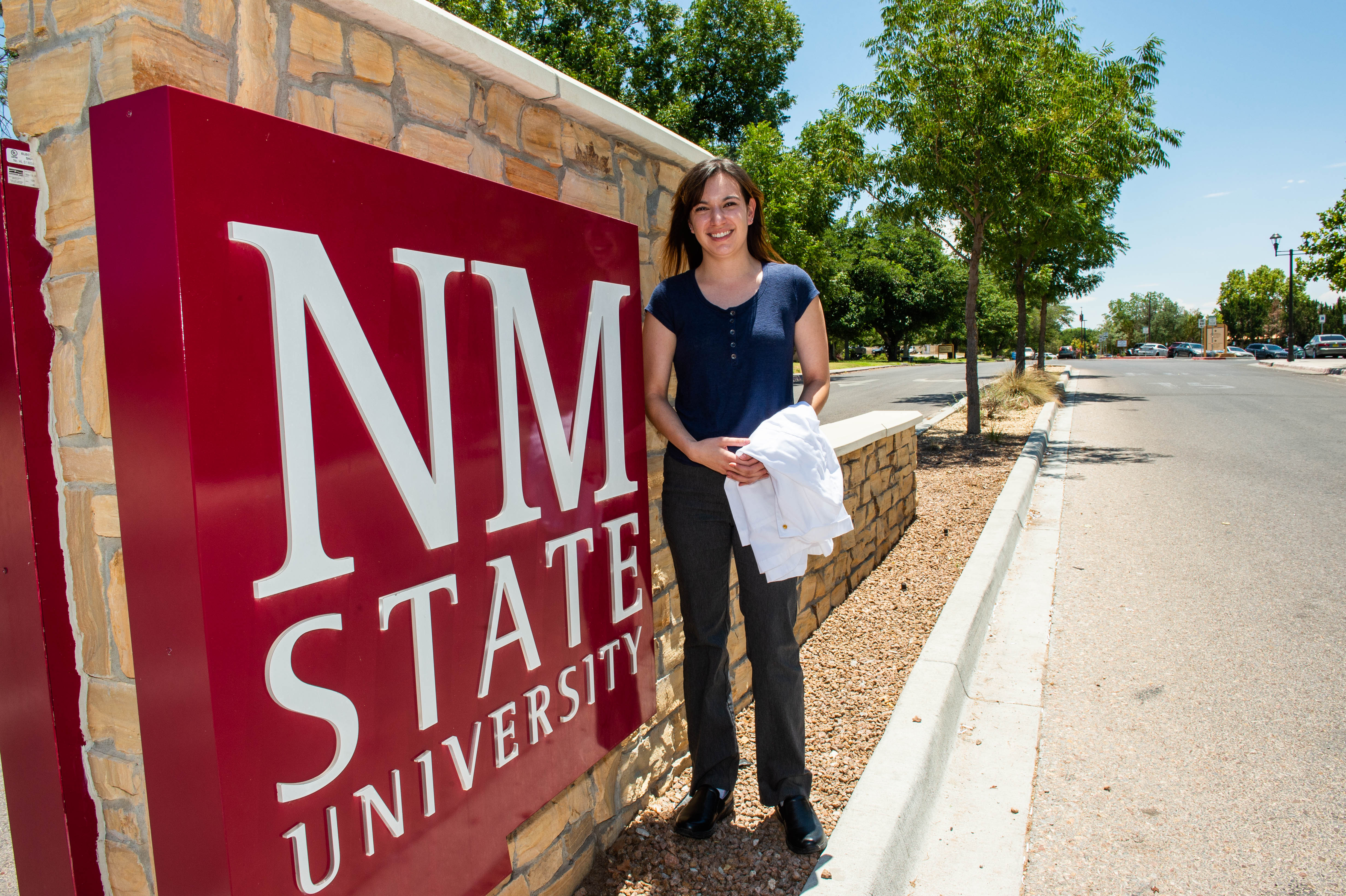 Woman standing near an NMSU sign. 
