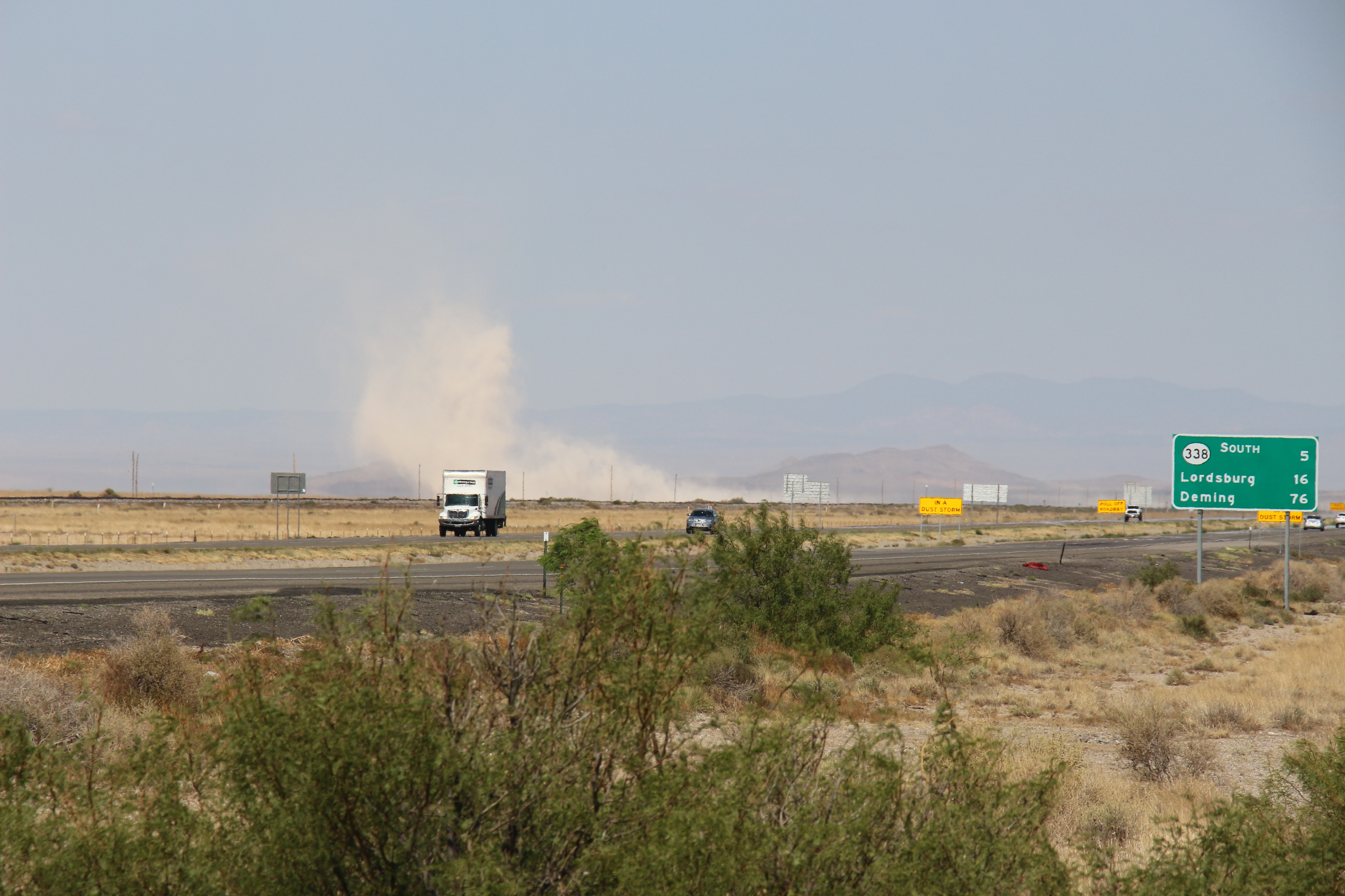 Vehicles drive past a dust storm