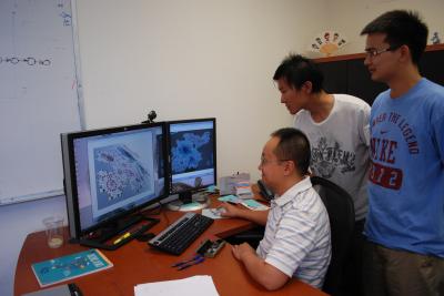 Professor and two students gathered around computer