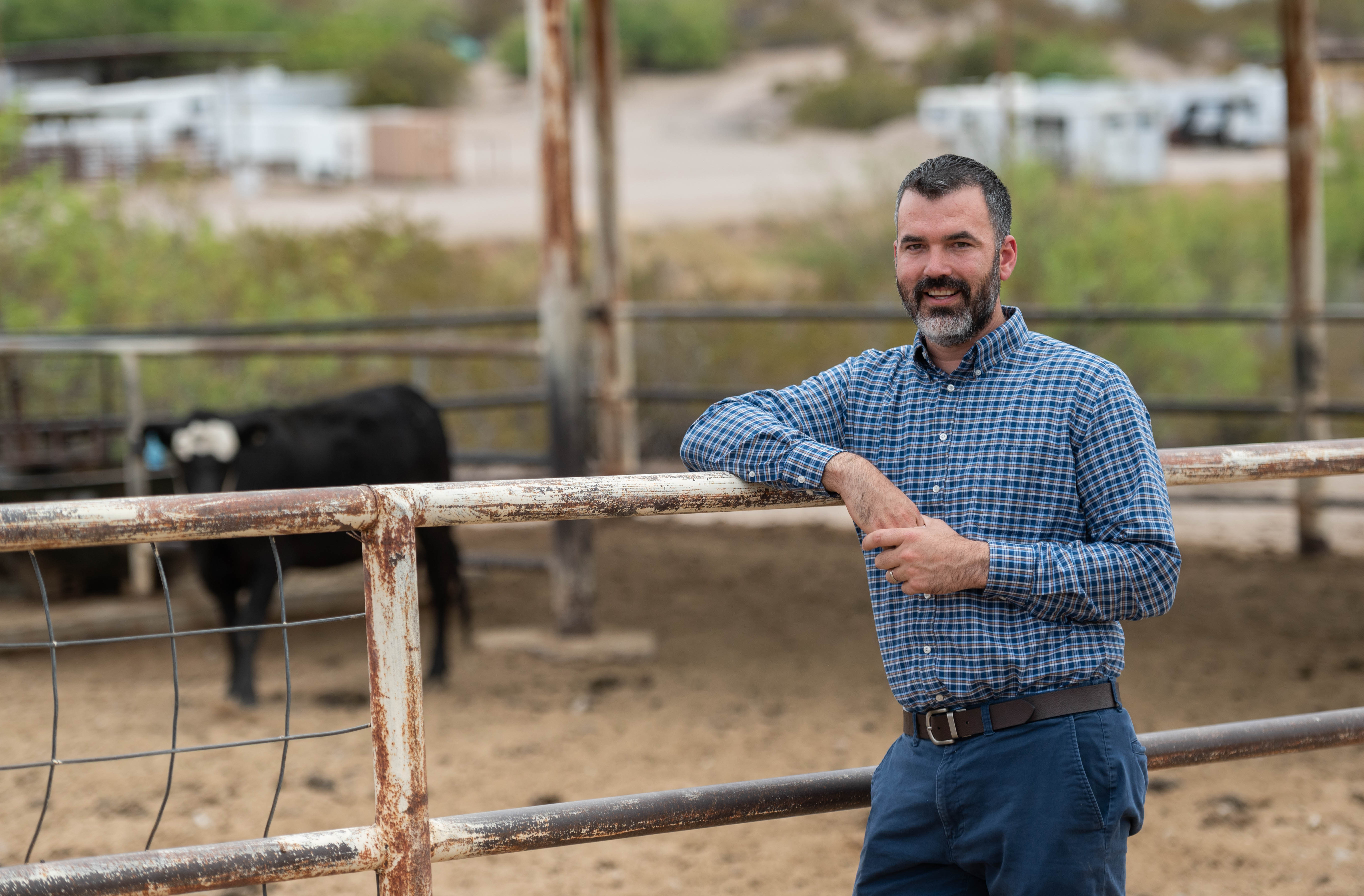Man standing outdoors next to a cattle pen