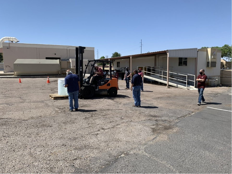 People watching a forklift operator outside in a parking lot.