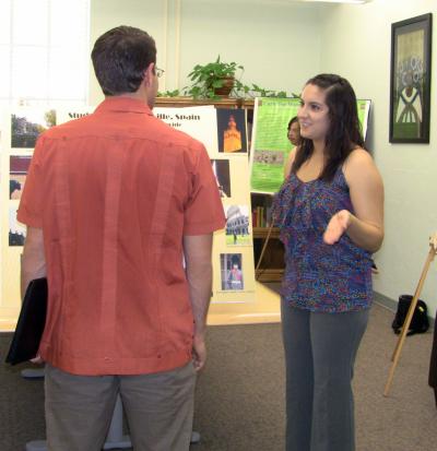 Young woman standing explaining presentation to man with back turned to camera