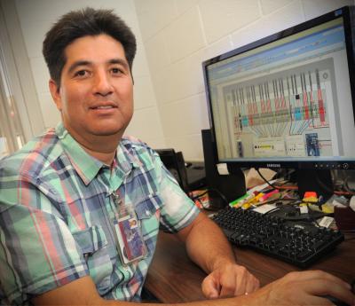 Pat Chavez, energy systems manager at NMSU, sits in front of his computer, demonstrating a software program he uses to manage and monitor energy use at NMSU.