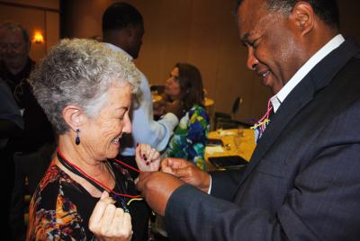 Caucasian woman on left receives a symbol of appreciation from African American man on right.