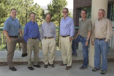 Jessie Nichols, Pete Pittman, Martin Piltch, Thomas Lienert, Marc Robbins and Wynn Christensen are photographed standing outside with pine trees in the backgroud