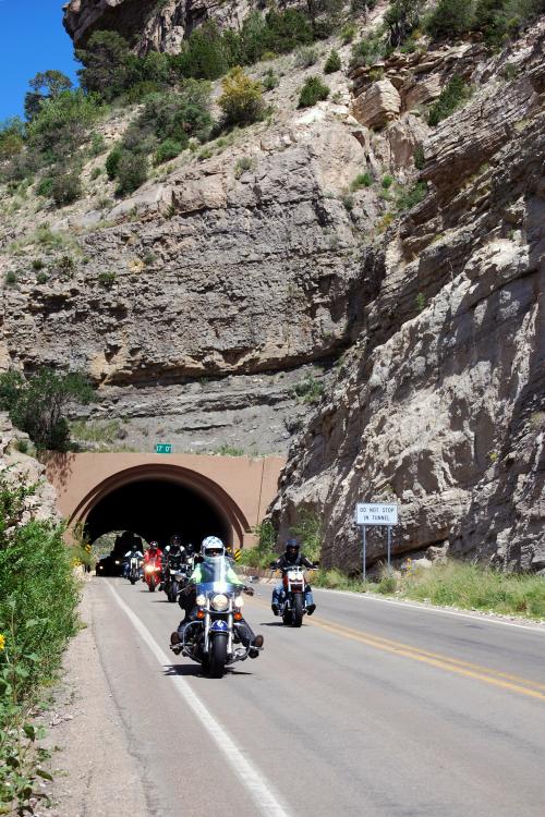 Motorcycles on a highway near the entrance to a tunnel.