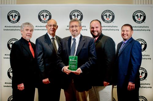 Man holding award with other men around