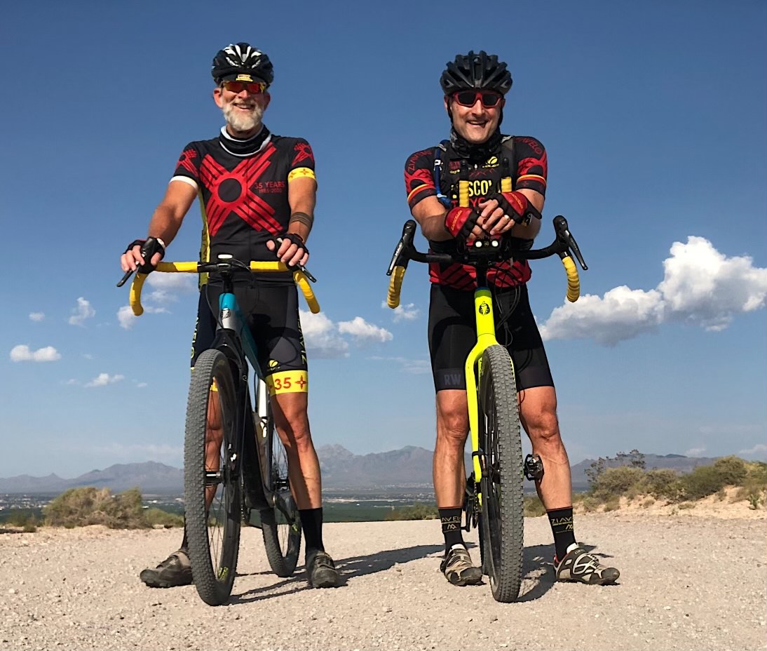 Two men standing with their bikes.