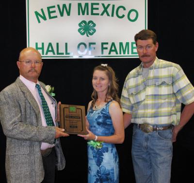 Two men and a lady standing in front of the New Mexico 4-H Hall of Fame sign.