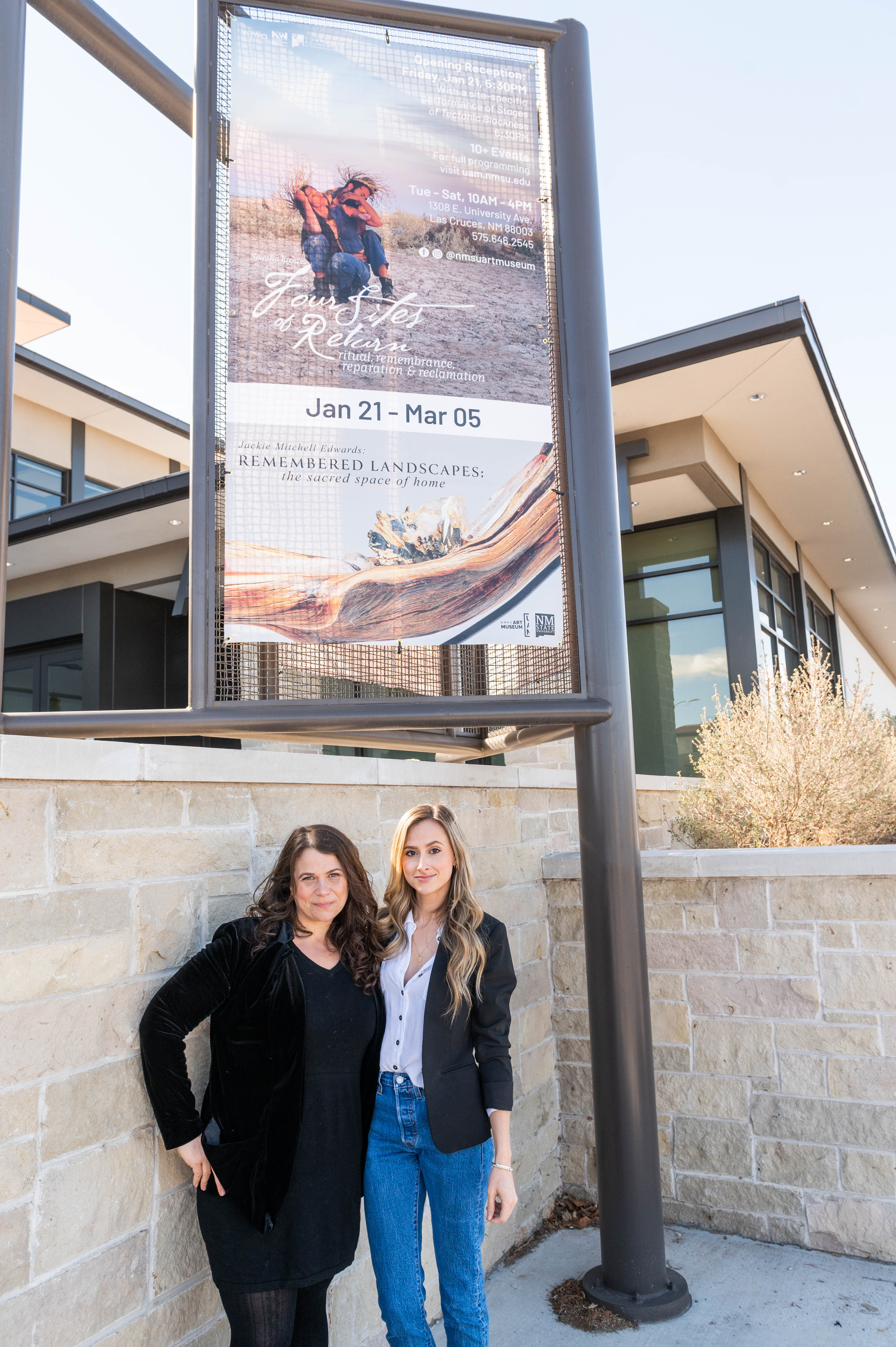 Two women standing under a sign