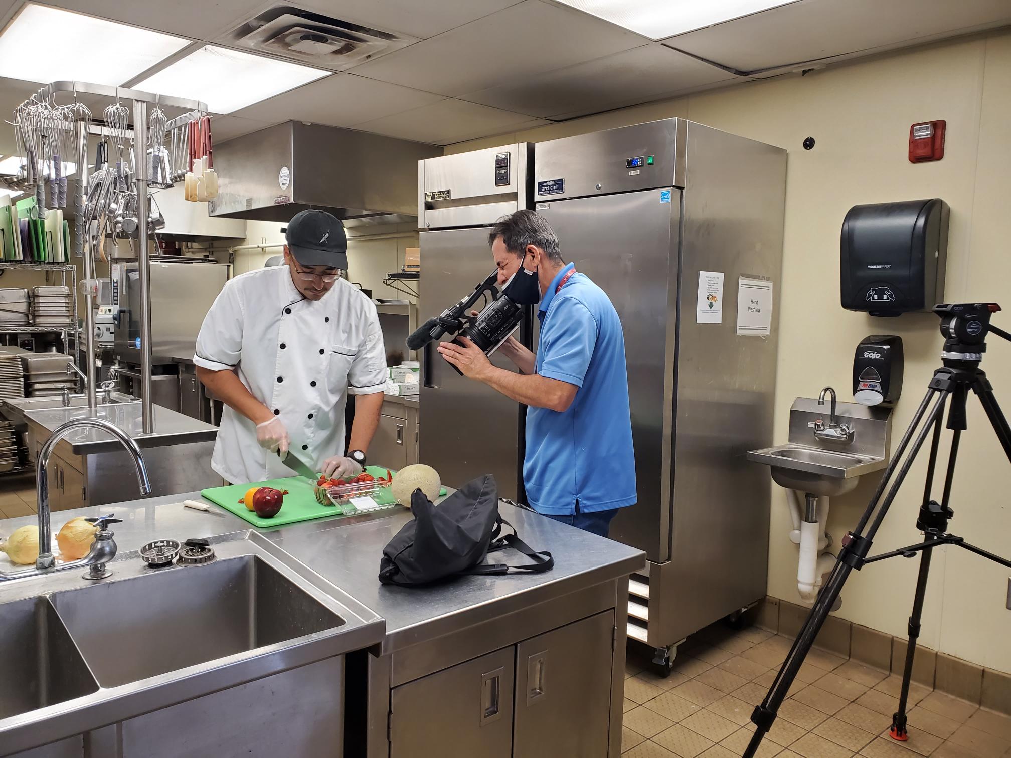 Art Ruiloba, right, films Gilbert Morales, a New Mexico State University alumnus who graduated from the School of Hotel, Restaurant and Tourism Management, cutting fruit for a new promotional video for the HRTM program. (Courtesy)